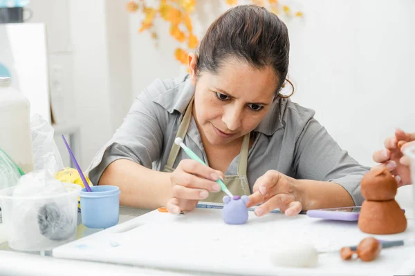 Hispanic woman working in her pastry shop - Latina woman working with fondant to decorate a cake - entrepreneur pastry chef - woman making craft with clay