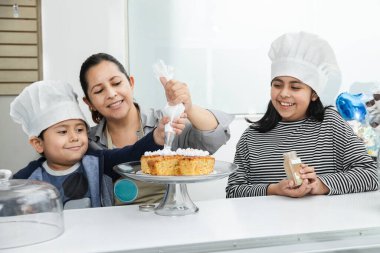 Latin bir annenin çocuklarıyla pasta süslemesi - İspanyol çocuklarının anneleriyle mutfakta eğlenmesi - pasta çocukları