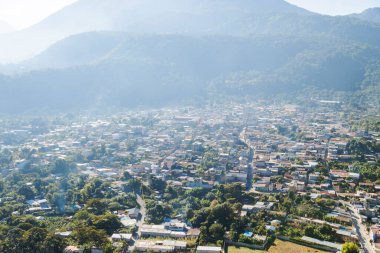 Sabahları Atitlan Gölü 'ndeki San Juan la Laguna' nın havadan görünüşü - Dağlarla çevrili küçük bir kasaba ve güneş ışığı olan volkanlar.