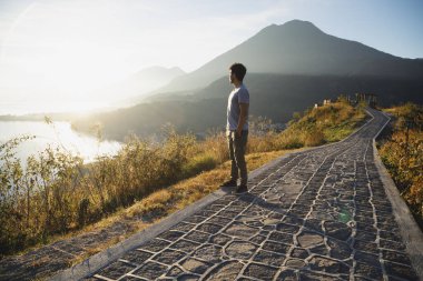 Genç adam dağın tepesinde Atitlan Gölü 'nde güneşin doğuşunu seyrediyor genç İspanyol gezgin Guatemala Gölü' nde güneşin doğuşunu seyrediyor.