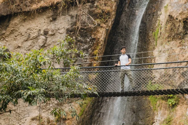 Joven Hispano Caminando Sobre Puente Colgante Medio Del Bosque Con — Foto de Stock