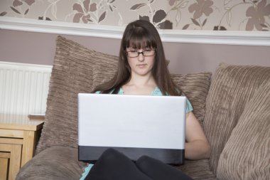 Bir leptop kullanarak koltukta oturan