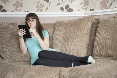 Tablet okuma kanepede oturan genç kadın