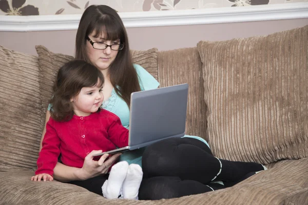 Anne ve kızı bir dizüstü bilgisayar izlerken