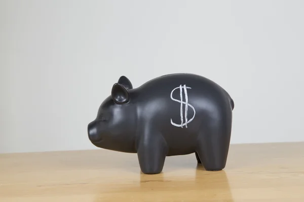 Saving the dollars in a black piggy bank — Stock Photo, Image