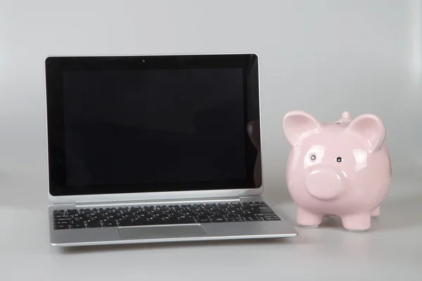 Piggy bank rosa ao lado do laptop aberto — Fotografia de Stock