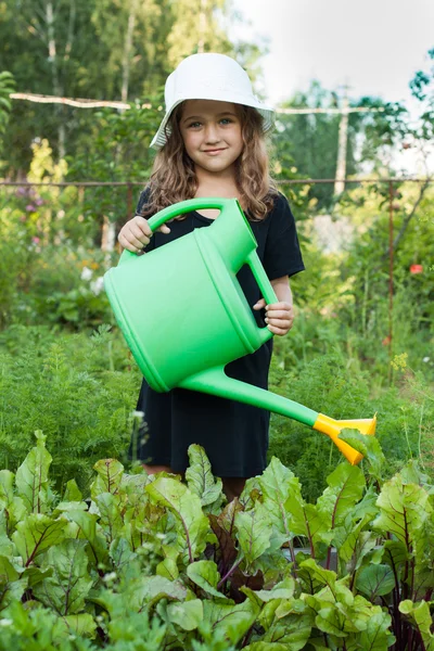 Bambina in cappello bianco e vestito nero irrigazione barbabietole lago verde . — Foto Stock