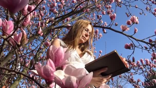 Leitura favorita no jardim Magnolia florido é um verdadeiro deleite . — Vídeo de Stock