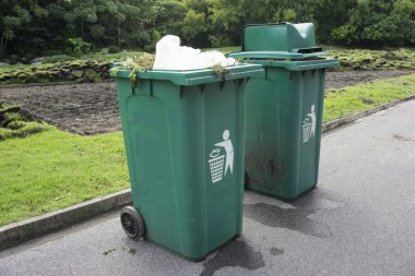 Full green garbage bin on road