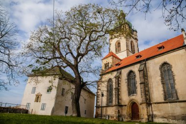 Eski okul binası ve ortaçağ Katolik kilisesi Aziz Peter ve Paul Kilisesi güneşli bir sonbahar gününde Melnik Kalesi, Yüksek Saat Kulesi, Merkez Bohemya, Çek Cumhuriyeti, 14 Kasım 2020