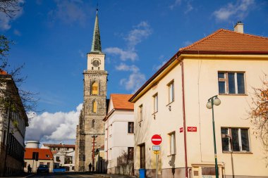 Ortaçağ Katolik kilisesi Aziz Jilji 'nin güneşli sonbahar gününde yüksek saat kulesi, sokak manzarası, Nymburk, Merkez Bohemya, Çek Cumhuriyeti, 17 Kasım 2020