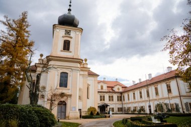 Loucen Rococo Kalesi, 22 Kasım 2020 'de Çek Cumhuriyeti' nin başkenti merkez Bohemya 'da sonbahar günü Bakire Meryem' in Varsayımı Kilisesi ile çevrili geniş bir İngiliz parkı, Romantik Barok Şatosu ile çevrilidir.