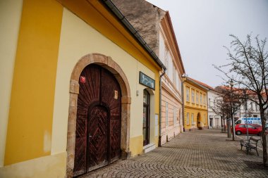 Bulutlu bir sonbahar gününde Husovo Meydanı, Cesky Brod 'un eski tarihi merkezinde renkli tarihi binaları olan pitoresk bir cadde, Merkez Bohemya, Çek Cumhuriyeti, 28 Kasım 2020