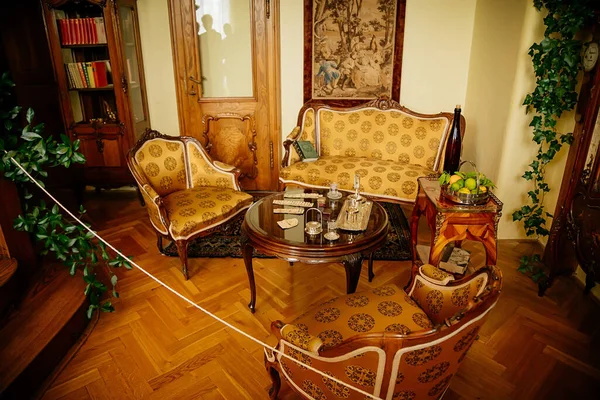 Radun kalesinin iç mimarisi, Neo-Klasik şato, sarı kütüphane, barok ve rokoko oyulmuş ahşap mobilyalar, koltuklar, iskambil kağıtları, gümüş kaplar ve kitaplarla dolu masa, Çek Cumhuriyeti, 06 Temmuz 2018