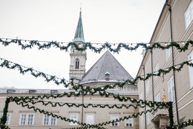 Domplatz Meydanı 'nda el yapımı renkli tatil süslemeleri, Fransisken Kilisesi Kulesi, geleneksel gelişim, Salzburg, Avusturya' da açık havada yeşil Noel ağacı dalları, 05 Aralık 2017
