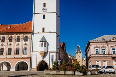 Ana kasaba Barış Meydanı, Gotik Beyaz Şehir Binası Kulesi, Mikulov Kapısı, Ortaçağ dar sokağı, Rönesans ve Barok tarihi binaları, atari salonu, güneşli gün, Kadan, Çek Cumhuriyeti, Nisan 04, 2021