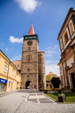 Galerisi ve saati olan ortaçağ gotik kulesi, Valdice kapısı veya Valdicka brana, güneşli bir günde Büyük St. James 'in barok kilisesi, Bohemya Cenneti veya Cesky Raj, Jicin, Çek Cumhuriyeti, 01 Mayıs 2021