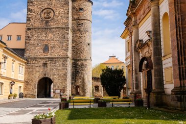 Galerisi ve saati olan ortaçağ gotik kulesi, Valdice kapısı veya Valdicka brana, güneşli bir günde Büyük St. James 'in barok kilisesi, Bohemya Cenneti veya Cesky Raj, Jicin, Çek Cumhuriyeti, 01 Mayıs 2021
