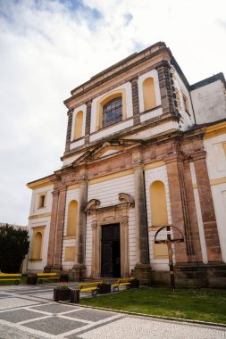 Barok ve neoklasik stil St. James Kilisesi güneşli bir günde, sarı banklar ve çiçekler, tarihi merkez, Bohemya Cenneti veya Cesky Raj, Jicin, Çek Cumhuriyeti, 1 Mayıs 2021