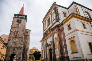 Galerisi ve saati olan ortaçağ gotik kulesi, Valdice kapısı veya Valdicka brana, güneşli bir günde Büyük St. James 'in barok kilisesi, Bohemya Cenneti veya Cesky Raj, Jicin, Çek Cumhuriyeti, 01 Mayıs 2021