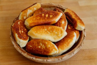 Yeşil soğanlı ve yumurtalı leziz kızarmış turtalar, köfteler veya pirozhki, geleneksel Rus hamur işi mutfağı, ev yapımı kekler, ahşap arka planda beyaz tabak, yiyecek Slavonik konsepti, kırsal köy