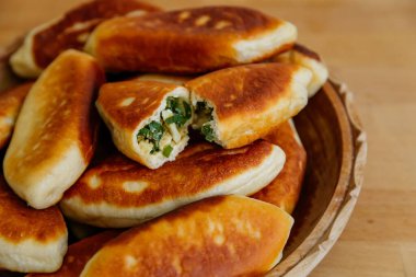 Yeşil soğanlı ve yumurtalı leziz kızarmış turtalar, köfteler veya pirozhki, geleneksel Rus hamur işi mutfağı, ev yapımı kekler, ahşap arka planda beyaz tabak, yiyecek Slavonik konsepti, kırsal köy