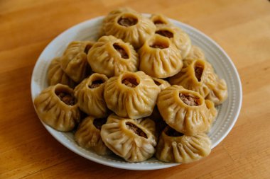 Buharda pişirilmiş milli Moğol yemeği köfte Buuz kıyma, beyaz tabak, ahşap masa Doğu Sibirya Buryats çanak poz, Sulu kıymalı el yapımı hamur gömleği, üst görünümde.