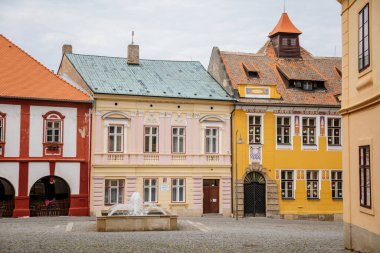 Trckovo meydanının kaldırım taşı caddesi, renkli evler, güneşli yaz gününde bir çeşme, ağaç ve yeşil çimenlik tarihi merkez, ortaçağ şehri Opocno, Çek Cumhuriyeti, 12 Haziran 2021