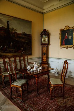 Krasny Dthe Chateau, Kuzey Bohemya, Çek Cumhuriyeti, 19 Haziran 2021: Kale içi, barok mobilyalar, sandalye ve çay seti oyulmuş oturma odası ahşap masa, sekreter ve antika büyükbaba saati.