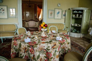 Krasny Dthe Chateau, Kuzey Bohemya, Çek Cumhuriyeti, 19 Haziran 2021: Şato içi, yemek odasında beyaz rokoko mobilya, tabaklar, pasta ve meyveli barok dolap.