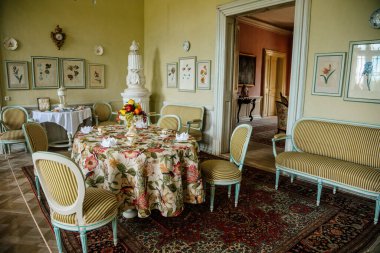 Krasny Dthe Chateau, Kuzey Bohemya, Çek Cumhuriyeti, 19 Haziran 2021: Kale içi, yemek odasında beyaz barok mobilyalar, masa örtüsü ile kaplı çiçek desenli ocak, seramik kiremitli ocak.