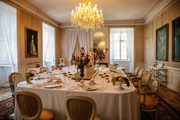 Krasny Dthe Chateau, Kuzey Bohemya, Çek Cumhuriyeti, 19 Haziran 2021: Kale içi, yemek odasında barok mobilyalar, akşam yemeği, şarap kadehleri, beyaz masa örtüsü üzerinde porselen servis edilen büyük masa.