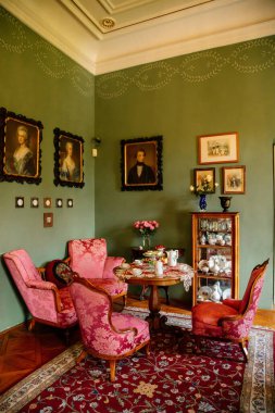 Velke Brezno, Çek Cumhuriyeti, 26 Haziran 2021: Şato Velke Brezno, barok mobilyalı kale içi, porselenli ahşap oyma büfe, yumuşak sandalyeli masa ve kırmızı kanepe, çaydanlık ve fincanlar.