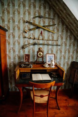 Velke Brezno, Çek Cumhuriyeti, 26 Haziran 2021: Şato Velke Brezno, barok mobilyalı kale içi, pencere kenarındaki tahta yazı masası ve sandalye, antik silahlar, kılıçlar ve silah, retro saat.