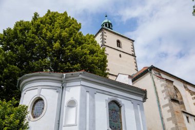 Benesov nad Ploucnici, Kuzey Bohemya, Çek Cumhuriyeti, 26 Haziran 2021: Bakire Meryem 'in Doğuşu' nun eski gotik kilisesi. Yazın güneşli bir günde eski Saksonya Rönesans Kalesi yakınlarında taş kuleleri var..