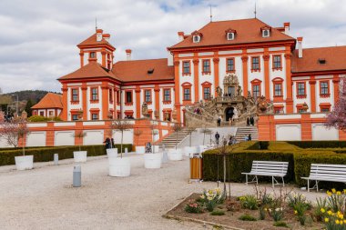 Prag, Çek Cumhuriyeti, 25 Nisan 2021: Troja kalesi, tarihi şato ve bahar günü bir bahçeyle çevrili kırmızı ve beyaz barok sarayı, taş heykellerle süslenmiş merdivenler.