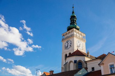 Mikulov, Güney Moravya Bölgesi, Çek Cumhuriyeti, 05 Temmuz 2021: Ortaçağ kilise meydanı ve St. Wenceslas Kilisesi 'nin beyaz saat kulesi, yeşil kubbe ve güneşli yaz gününde kırmızı kiremit çatılar.