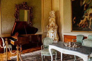 Valtice, Güney Moravya, Çek Cumhuriyeti, 04 Temmuz 2021: Kale içi, barok ahşap oyma mobilya, antika kuyruklu müzik odası, seramik seramik soba, yaldızlı çerçeveli uzun ayna.