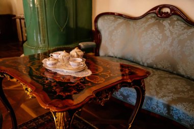 Jaromerice nad Rokytnou, Çek Cumhuriyeti, 06 Temmuz 2021: Barok ahşap oymalı mobilyalar, kanepe ve yumuşak koltuklar, masada porselen çay seti, yaldızlı çerçeveli tablolar.