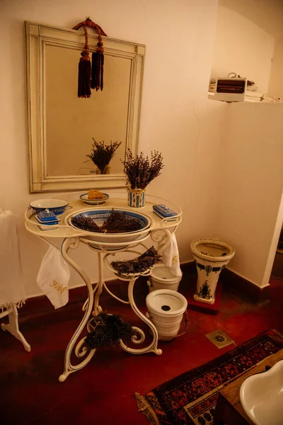 Jaromerice nad Rokytnou, Bohemya, Çek Cumhuriyeti, 06 Temmuz 2021: Barok ahşap oyma mobilyalar, banyo, ayna ve kurutulmuş lavanta buketleri ile beyaz ve mavi porselen lavabo.