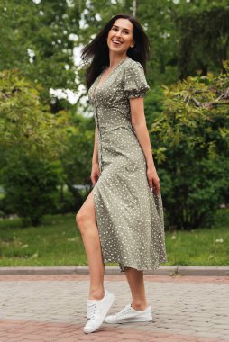 Şehir caddesinde poz veren zarif bir esmer kız. Şehrin arka planında şık giyinmiş güzel bir iş kadını..