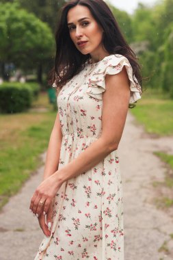 Şehir caddesinde poz veren zarif bir esmer kız. Şehrin arka planında şık giyinmiş güzel bir iş kadını..