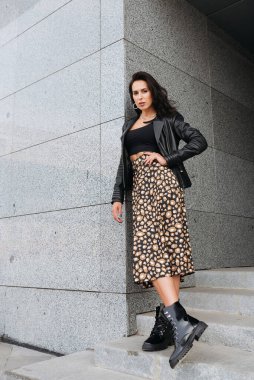 Şehir caddesinde poz veren zarif bir esmer kız. Şehrin arka planında şık giyinmiş güzel bir iş kadını..