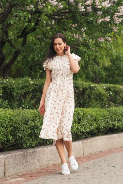 Şehir caddesinde poz veren zarif bir esmer kız. Şehrin arka planında şık giyinmiş güzel bir iş kadını..