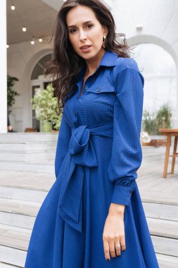 Şehir caddesinde poz veren zarif bir esmer kız. Şehrin arka planında şık giyinmiş güzel bir iş kadını..