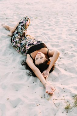 Zarif bir yaz elbisesi içinde genç ve güzel bir esmer ve güneş ışınlarında hasır şapkalı doğa yürüyüşünde.