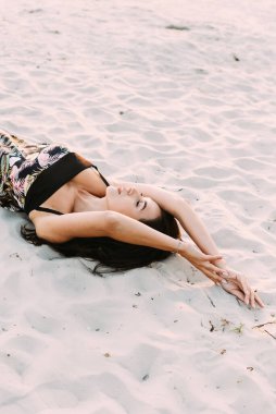 Zarif bir yaz elbisesi içinde genç ve güzel bir esmer ve güneş ışınlarında hasır şapkalı doğa yürüyüşünde.