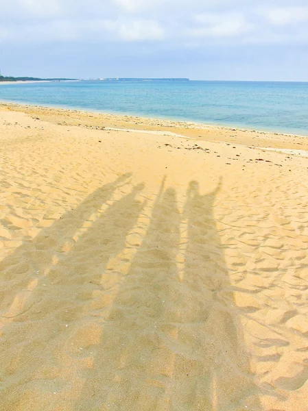 Skuggan av glada turister på stranden i sommar — Stockfoto