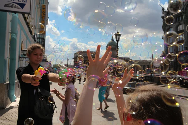 Flickan börjar upp såpbubblor på bakgrund av huvudsakliga ci — Stockfoto