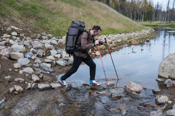 Turista pasa arroyo afluente usando postes de trekking —  Fotos de Stock